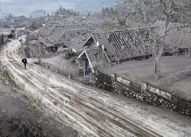 Một người dân đi gần những ngôi nhà bị bao phủ đầy tro bụi phun trào từ núi lửa Kelud tại ngôi làng Ngantang ở Malang, trên đảo Java, Indonesia.