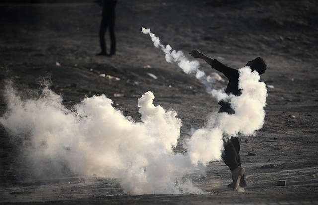 Người biểu tình ném lựu đạn hơi cay trả lại phía cảnh sát trên đường phố ở thủ đô Manama, Bahrain.