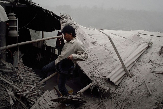 Người dân kiểm tra ngôi nhà bị sập bao phủ đầy tro bụi phun trào từ núi lửa Sinabung, Karo, Indonesia.