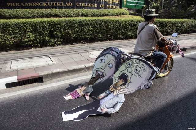 Người biểu tình chống chính phủ kéo hình biếm họa của Thủ tướng Thái Lan Yingluck Shinawatra và anh trai Thaksin trên đường phố ở thủ đô Bangkok.