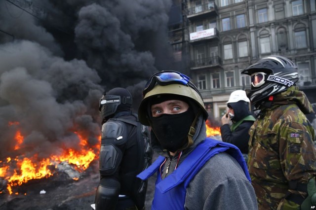 Người biểu tình đứng sau hàng rào trước cảnh sát chống bạo động ở Kiev, Ukraine.