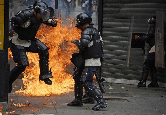 Cảnh sát nhảy tránh bom xăng của người biểu tình trong cuộc đụng độ ở Caracas, Venezuela.