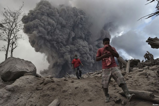 Người dân đi trên tro phun trào từ núi nửa Sinabung đang hoạt động ở North Sumatra, Indonesia.