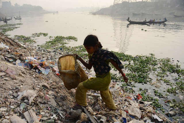 Một bé gái nhặt rác bên bờ sông ở Dhaka, Bangladesh.