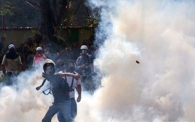 Người biểu tình đụng độ với cảnh sát chống bạo động trên đường phố ở Caracas, Venezuela.