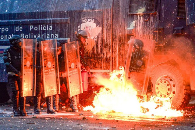 Cảnh sát cố gắng dập lửa từ bom xăng do người biểu tình ném trên đường phố ở Caracas, Venezuela.