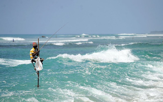 Một ngư dân ngồi trên cột câu cá ở ngoài khơi thị trận trấn Galle, Sri Lanka.