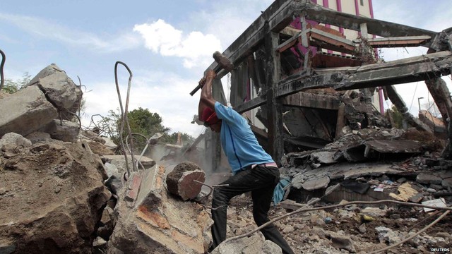 Một người đàn ông đập các tàng bê tông để lấy sắt từ các tòa bị sập sau trận động đất ở Managua, Nicaragua.
