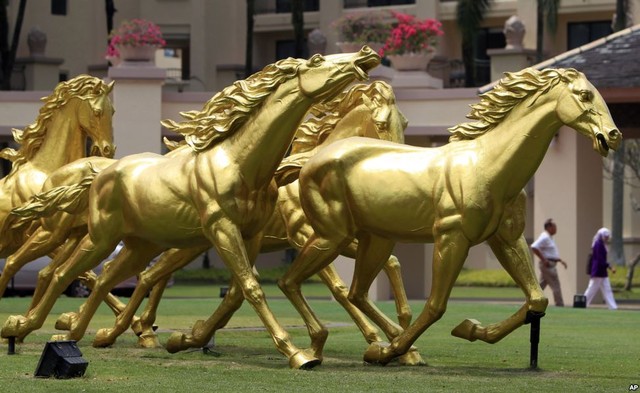 Mọi người đi qua những bức tượng ngựa được sơn vàng trước một khách sạn ở Kuala Lumpur, Malaysia.