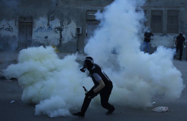 Một người biểu tình bỏ chạy khi bị cảnh sát bắn đạn hơi cay ở Meqsha, tây Manama, Bahrain.