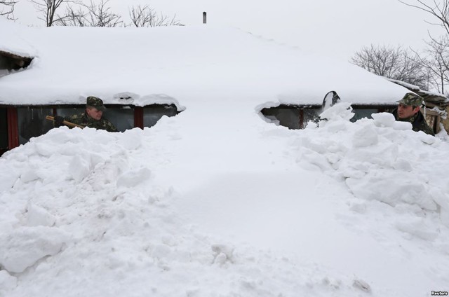 Các binh sĩ dọn tuyết trước một ngôi nhà sau trận bão tuyết mạnh ở ngôi làng Vadu Pasii, Bucharest, Romania.