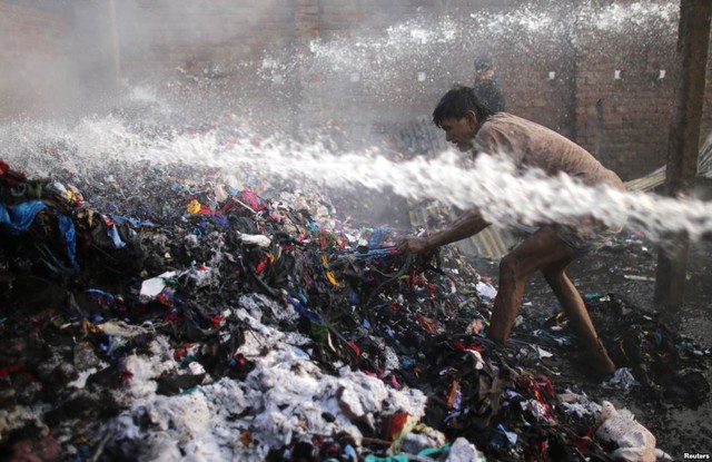 Người đàn ông cố gắng lấy những thứ còn dùng được từ nhà kho chứa cốt tông ở Dhaka, Bangladesh.