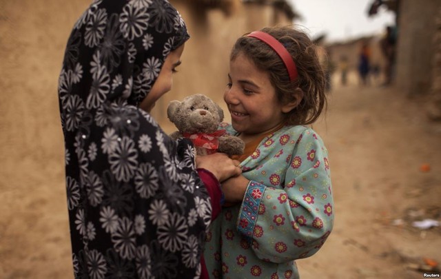 Một bé gái tị nạn người Afghanistan tặng gấu bông với dải ruy băng hình trái tim cho bạn vào ngày lễ Valentine tại một khu ổ chuột ở ngoại ô Islamabad, Pakistan.