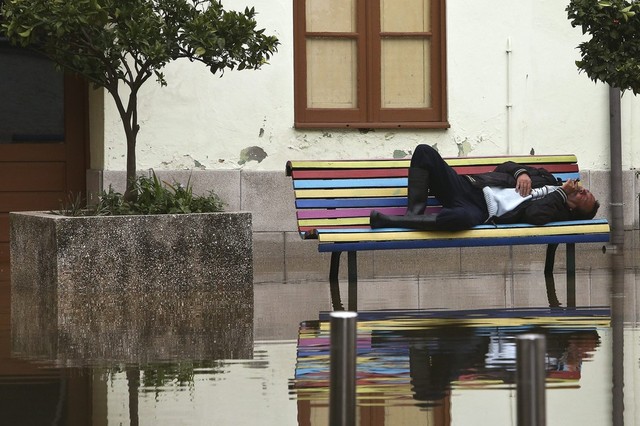 Người đàn ông nằm ngủ trên ghế bao quanh bởi nước lũ ở Agueda, Bồ Đào Nha.