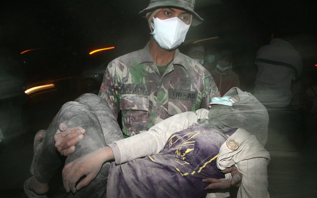 Một binh sĩ quân đội bế người dân bị ngất trong khi sơ tán sau khi núi lửa Kelud phun trào trên đảo Java, Indonesia.