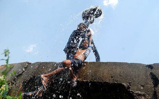 Trẻ em tắm mát dưới đường ống nước vỡ dưới trời nắng nóng ở ngoại ô thành phố Bhubaneswar, Ấn Độ.