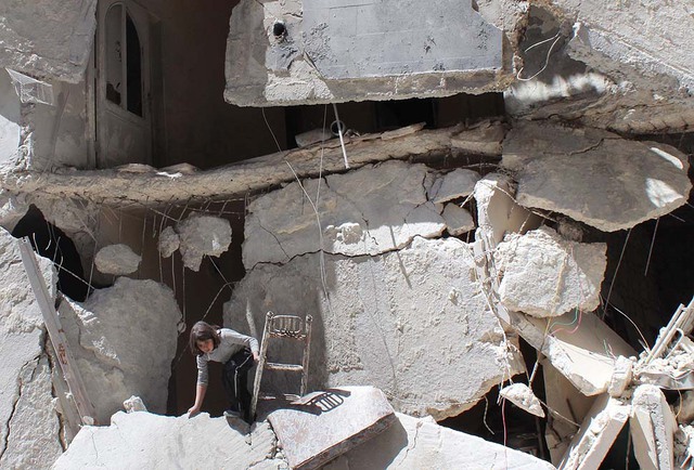 Một bé gái người Syria nhặt những thứ còn dùng được từ đống đổ nát sau khi tòa nhà nơi gia đình cô bé sống bị phá hủy trong cuộc không kích của quân đội chính phủ ở thành phố Aleppo.