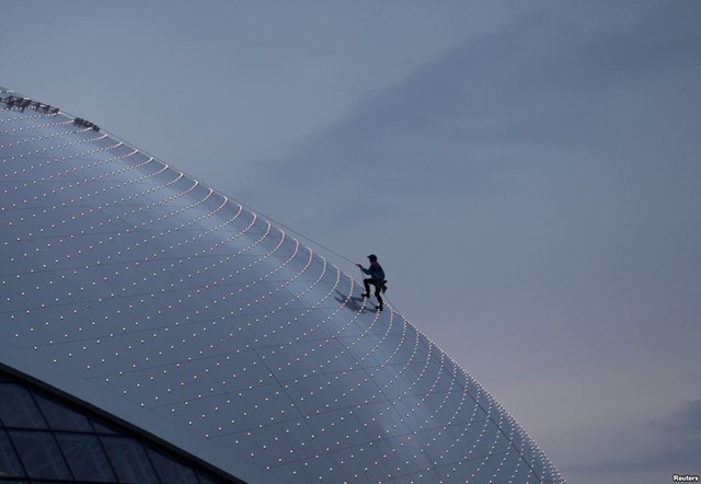 Một công nhân trèo lên mái của kiến trúc mái vòm Bolshoy Ice tại công viên Olympic Sochi 2014, Nga.