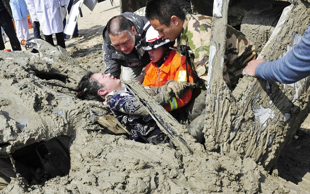 Nhân viên cứu hộ giải cứu thành công một phụ nữ bị mắc kẹt trong ô tô bao phủ đầy bùn trên đường phố ở Phúc Châu, Trung Quốc.