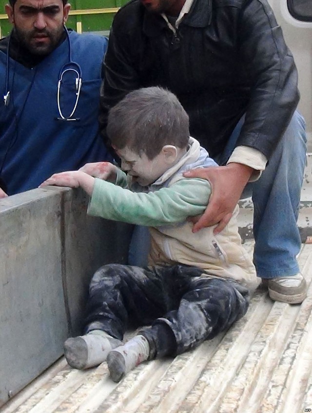 Mọi người giúp đỡ một em bé bị thương trong cuộc không kích của quân đội chính phủ nhằm vào một trường học ở Aleppo, Syria.