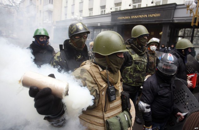 Một người đàn ông cầm bom khói khi người biểu tình chống chính phủ diễu hành trên phố ở Kiev, Ukraine.