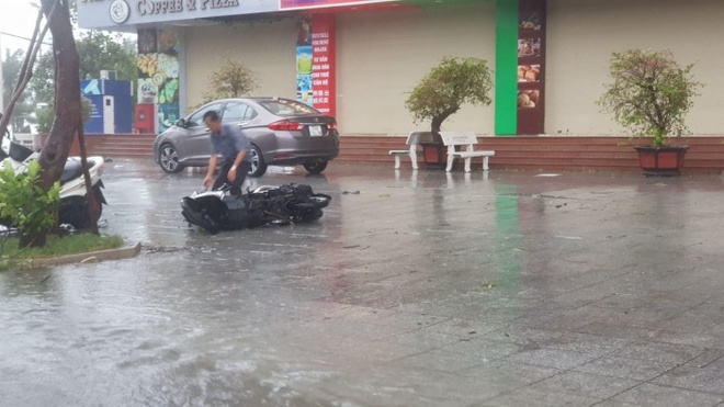 Nha Trang: Gió quật đổ hàng loạt xe máy trên đường, người dân nấp sau cột điện để tránh gió - Ảnh 1.