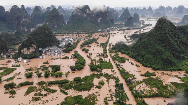 Lũ lụt dâng cao, người dân chèo thuyền đi lại trên phố - Ảnh 2.