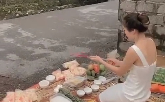Hình ảnh người phụ nữ trẻ đẹp mang đồ lễ tới trước nhà một "con nợ" thắp hương cúng bái để đòi nợ - ảnh cắt từ clip
