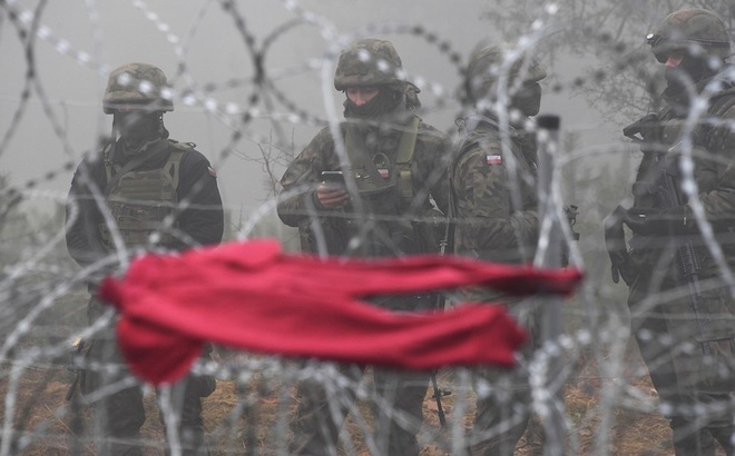 Binh sĩ Ba Lan đứng gác cạnh hàng rào dây thép gai sát một trại di cư trên vùng Grodno của Belarus trên tuyến biên giới. Ảnh: Sputnik