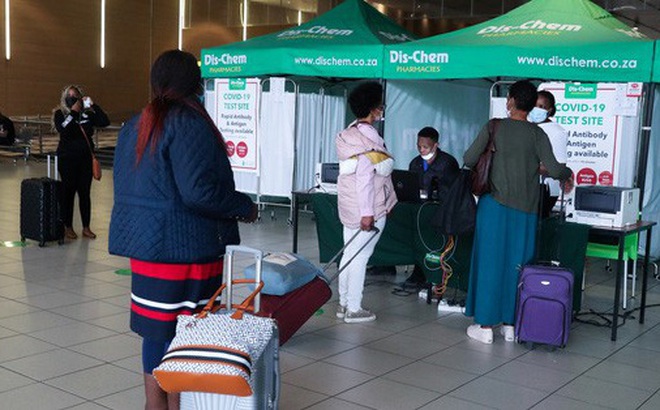 Nhân viên y tế lấy mẫu xét nghiệm cho hành khách trước khi lên chuyến bay đến Anh tại sân bay ở TP Johannesburg - Nam Phi, hôm 26-11 Ảnh: Reuters