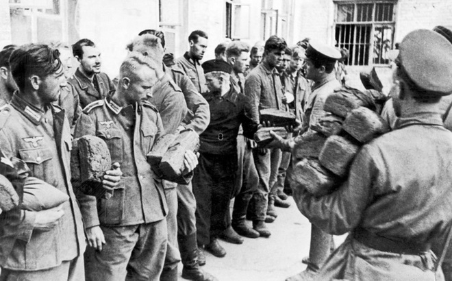 Chiến sĩ Hồng quân (bên phải) phát bánh mì cho tù binh Đức (bên trái) vào tháng 8/1941. Ảnh: Getty.