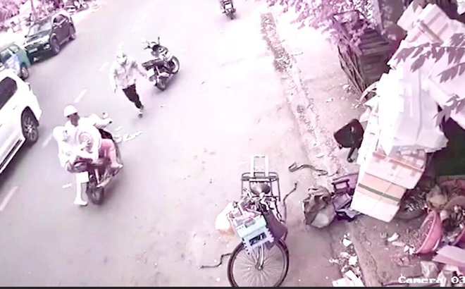 Cộng đồng mạng lên án việc một người phụ nữ dừng xe máy để đứa bé xuống nhặt tiền rồi rời đi. Ảnh chụp từ clip.