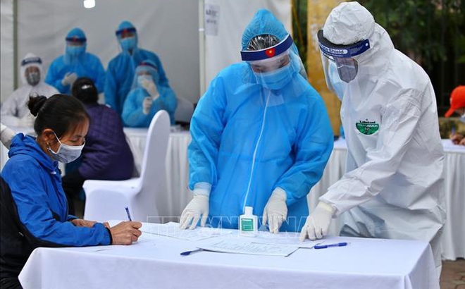 Nhân viên y tế hướng dẫn người dân khai vào tờ khai khi đến test nhanh COVID-19 ở Hà Nội. Ảnh: Minh Quyết/TTXVN.