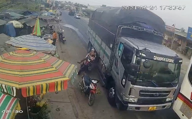 Hiện trường vụ tai nạn khiến 2 người đi xe máy bị xe tải hất văng, thoát chết trong gang tấc (Ảnh chụp màn hình camera an ninh)