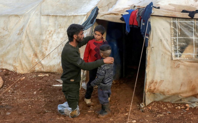 Anh Ahmad Hamra - một nạn nhân chiến tranh Syria - cùng 2 đứa con bên ngoài một trại tị nạn ở Aleppo. Ảnh: Today Online