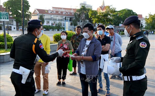 Cảnh sát phát khẩu trang miễn phí cho người dân để phòng lây nhiễm COVID-19 tại Phnom Penh, Campuchia. Ảnh: AFP/TTXVN