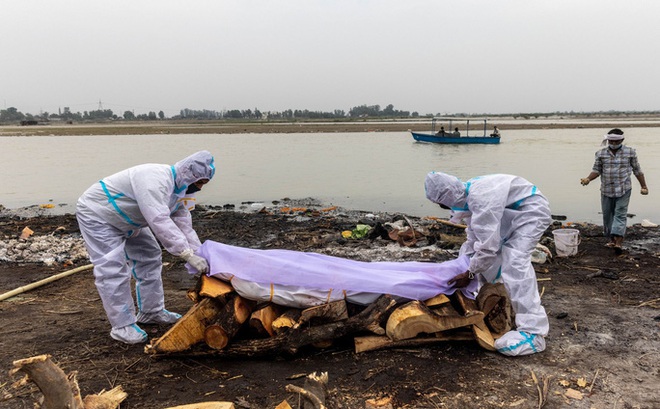 Các nhân viên y tế chuẩn bị hỏa táng thi thể nạn nhân Covid-19 bên bờ sông Hằng ở bang Uttar Pradesh - Ấn Độ hôm 6-5 Ảnh: REUTERS