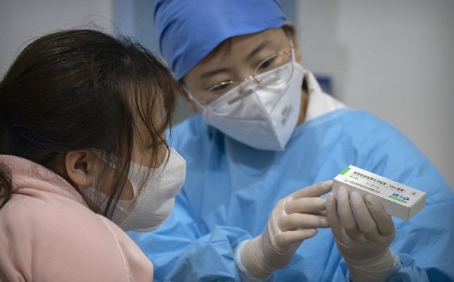 Nhân viên y tế giới thiệu về vaccine cho người tiêm tại một cơ sở ở Bắc Kinh, Trung Quốc. Ảnh: AP