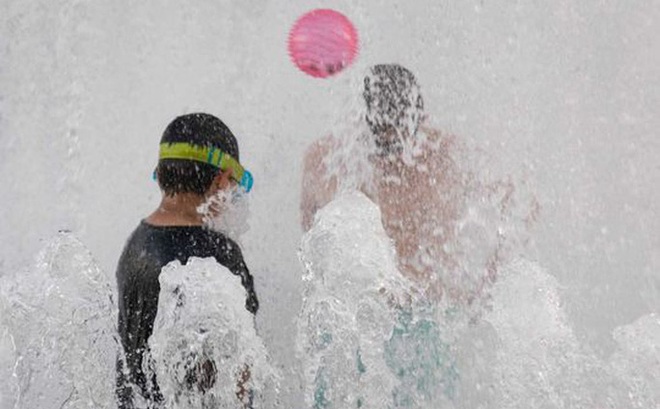 Trẻ em chơi đùa ở đài phun nước ven sông trong đợt nắng nóng ở Portland, Oregon hôm 26-6. Ảnh: Bloomberg