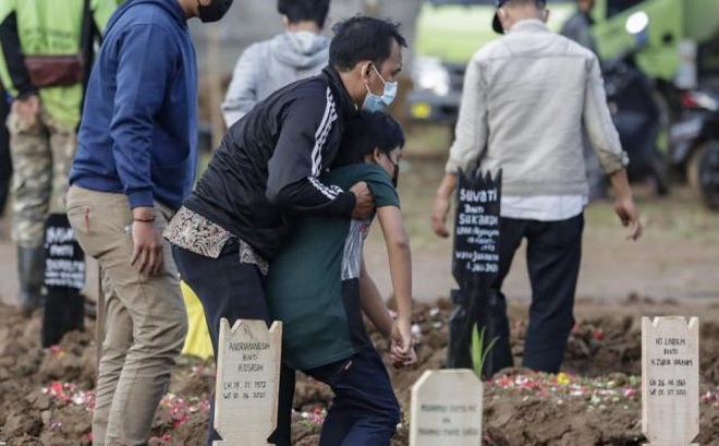 Người thân đứng bên mộ bệnh nhân tử vong vì Covid-19 ở Jakarta, Indonesia.