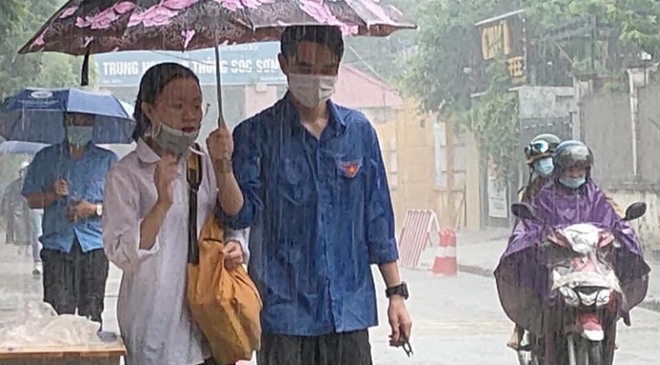 Chàng trai tình nguyện che ô cho các sĩ tử tránh cơn mưa bất ngờ, danh tính khiến dân mạng phát sốt - Ảnh 1.