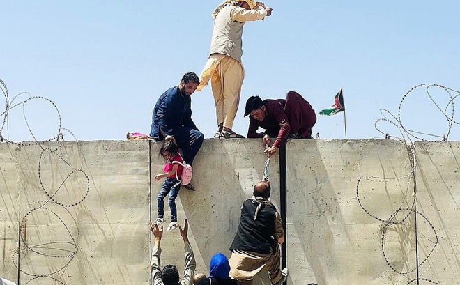 Người dân Afghanistan trèo tường vào sân bay Kabul. Ảnh: Getty