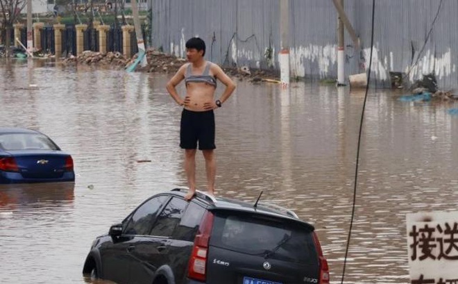 Một người đàn ông đứng trên ô tô bị nước lũ vây quanh ở thành phố Trịnh Châu, tỉnh Hà Nam, Trung Quốc hôm 22/7. Ảnh: Reuters