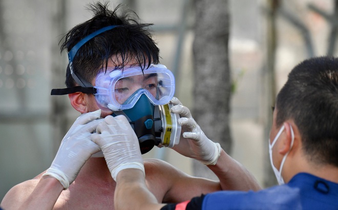 Người đàn ông giúp một tình nguyện viên tháo mặt nạ sau khi phun khử khuẩn ở Hạ Môn, Phúc Kiến. Ảnh: Tân Hoa xã