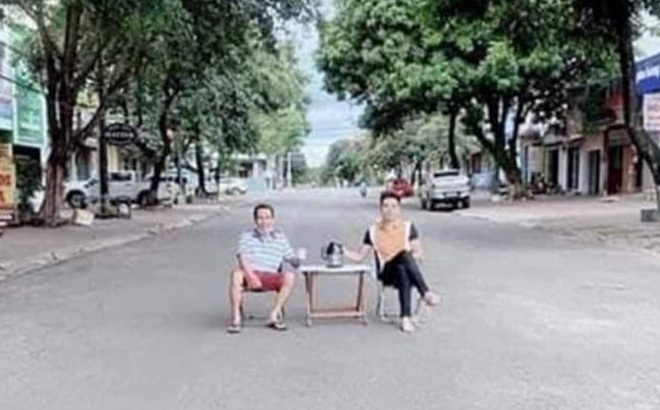 Hai người ngồi ở bàn giữa đường để "uống trà". Ảnh: MXH/báo Công lý