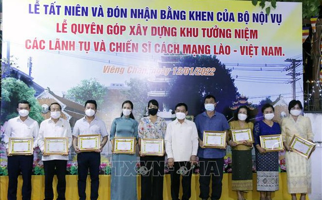 Bộ trưởng Nội vụ Lào, ông Thongchan Manixay (giữa) với các cá nhân và tập thể người Việt có nhiều thành tích trong công tác cứu trợ và vận động cứu trợ cho người dân Lào gặp thiên tai, dịch bệnh trong thời gian qua.