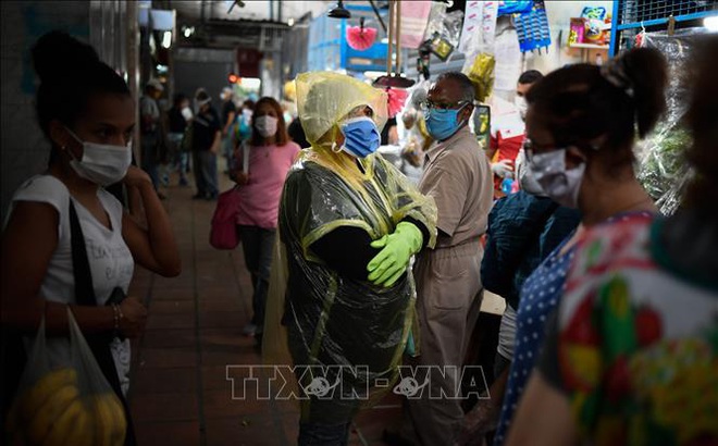 Người dân đeo khẩu trang và găng tay phòng lây nhiễm COVID-19 khi đi mua hàng tại Caracas, Venezuela. Ảnh tư liệu: AFP/TTXVN