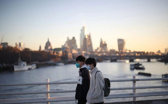 Hai thanh niên đeo khẩu trang khi đi bộ ở London. Ảnh: Reuters