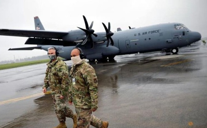 Hai quân nhân Mỹ đi cạnh chiếc trực thăng vận tải C-130 trong căn cứ quân sự Yokota, Nhật Bản. (Ảnh: Reuters)