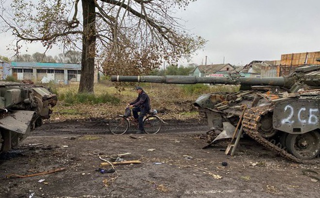 Dân địa phương đạp xe ngang qua những chiếc xe tăng Nga bị bỏ lại ở làng Kurylivka, vùng Kharkiv, Ukraine ngày 1-10 - Ảnh: REUTERS